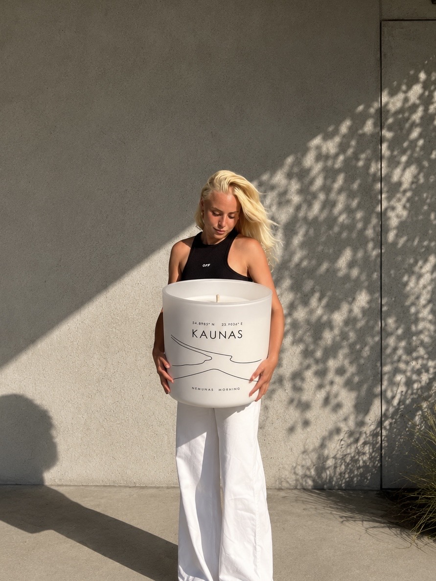 A Nida Journey candle held in daylight outside a Lithuanian studio wall